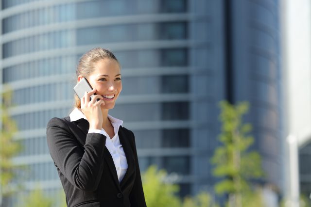 Happy businesswoman talking on phone and walking in the street
